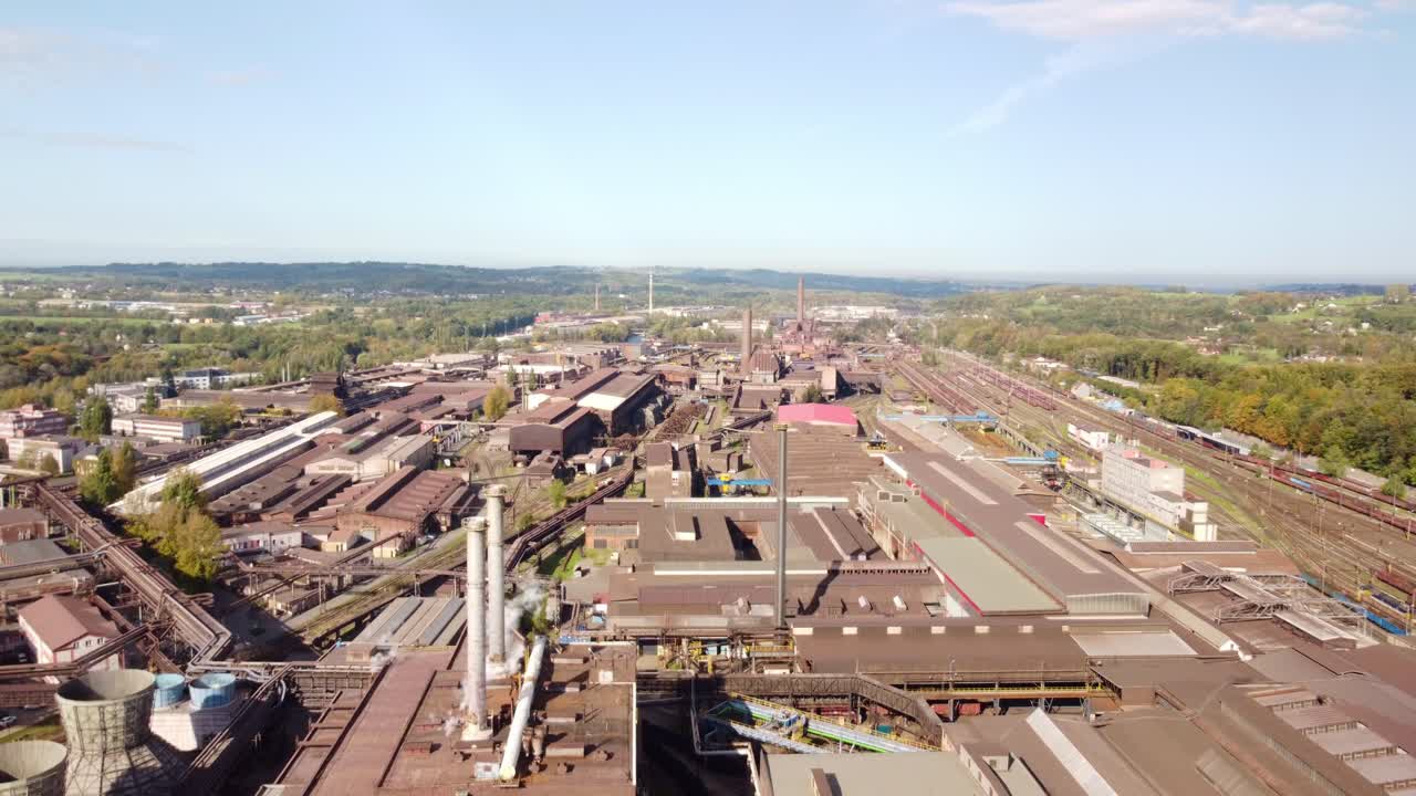 Industrial overview of Trinec steel factory with large equipment and surrounding urban area, dense complex building network by train tracks