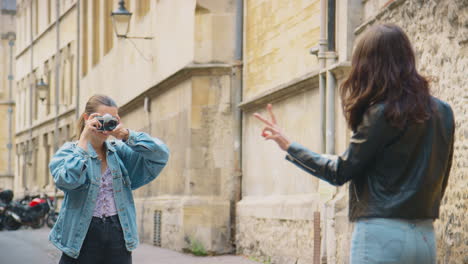 same sex female couple taking photos of each other on retro digital camera around oxford uk together