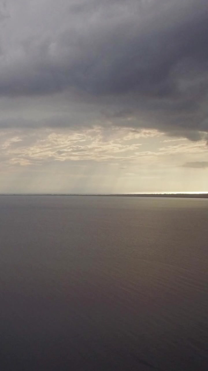 Aerial view of quiet sea, grey clouds in evening sky