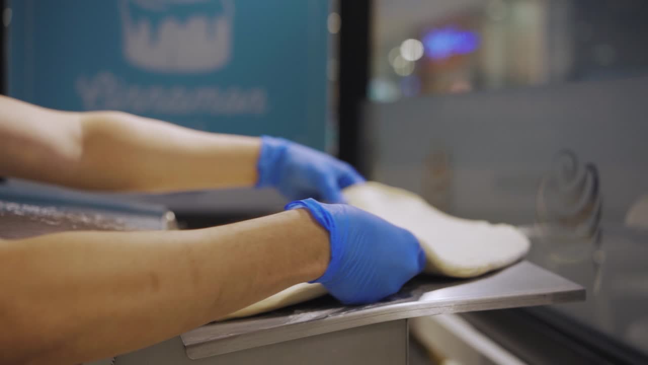 panadero aplanando la masa en la máquina dentro de la panadería