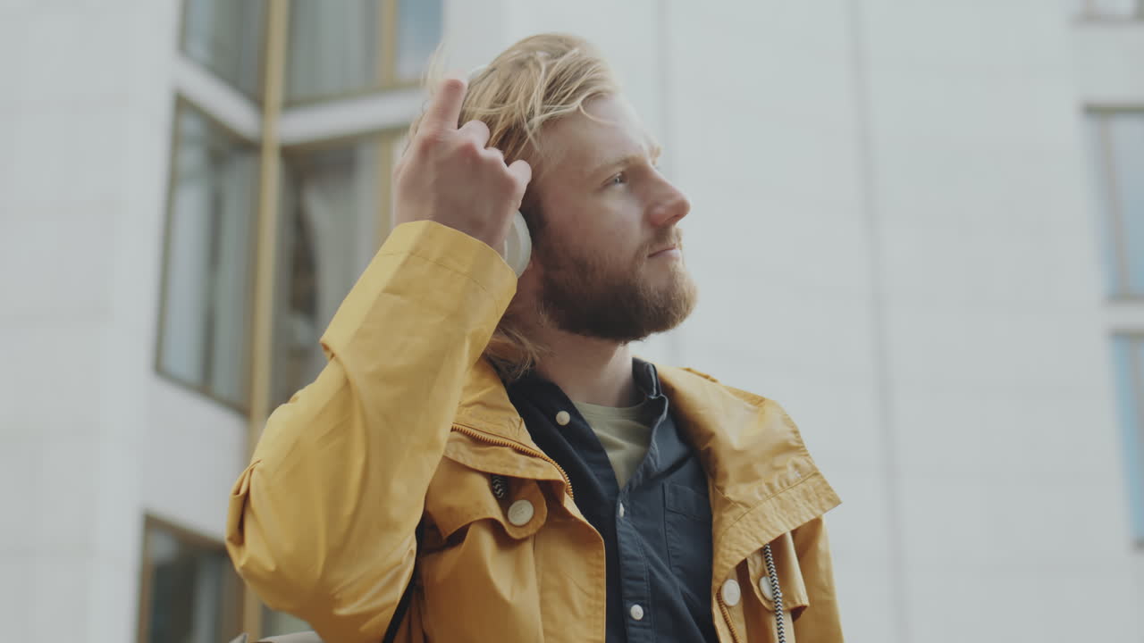 Man Putting on Headphones while Standing Outdoors