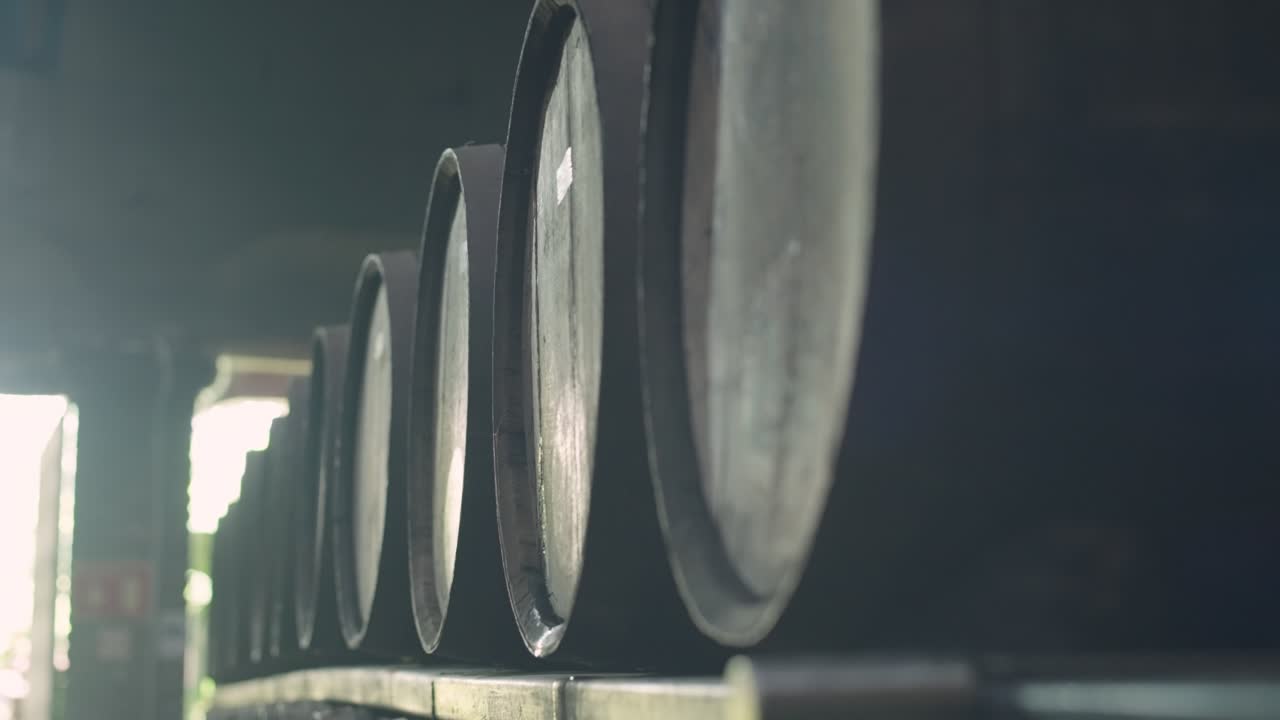 Side view of multiple Mexican wine barrels stored in a dimly lit storage hall