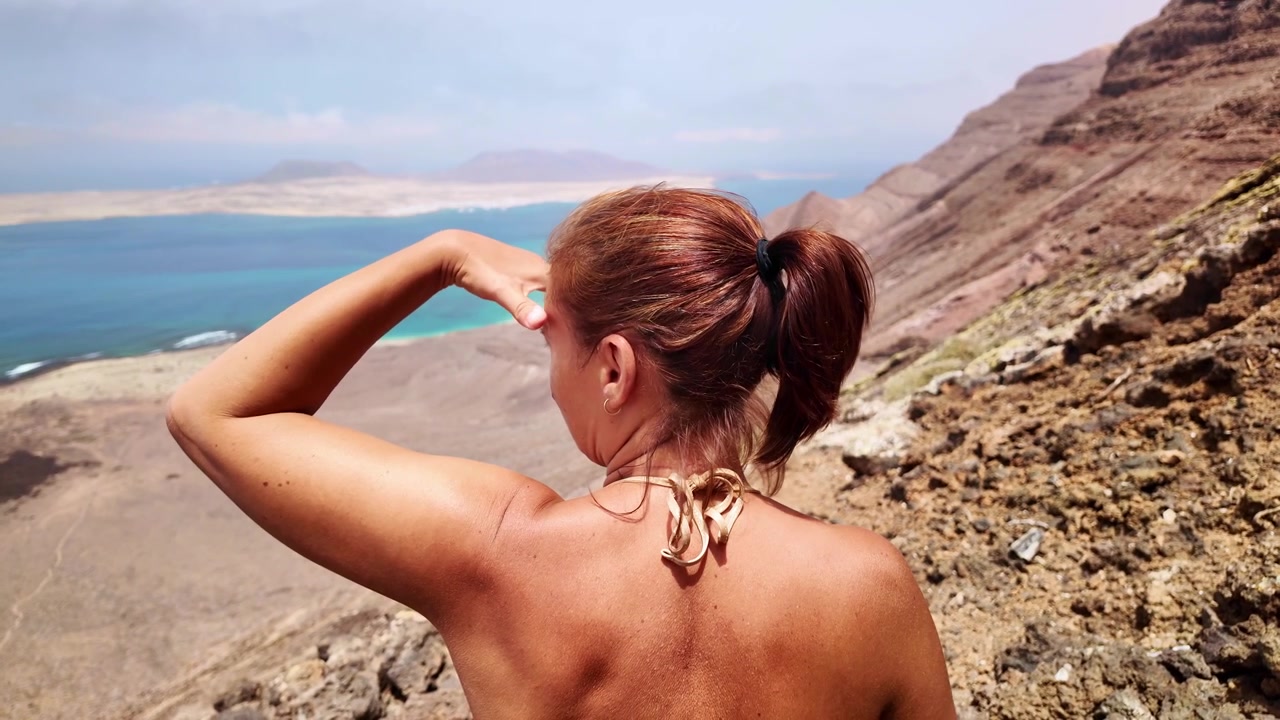 Donna di spalle che osserva la spiaggia del Risco a Lanzarote