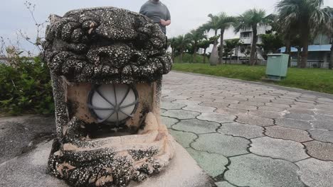 Hombre-Blanco-Obeso-Corriendo-Descalzo-Frente-A-La-Estatua-Del-León-Guardián-En-Un-Parque-Público-Tratando-De-Perder-Peso