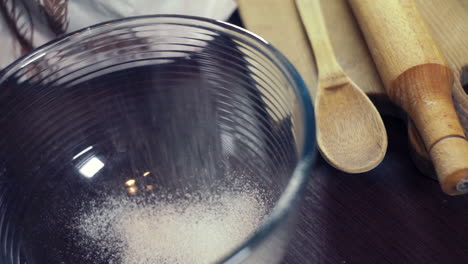 Powdered-sugar-for-icing-falling-in-a-deep-glass-bowl