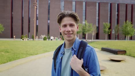 Portrait-of-male-university-student-standing-outside-the-university-campus