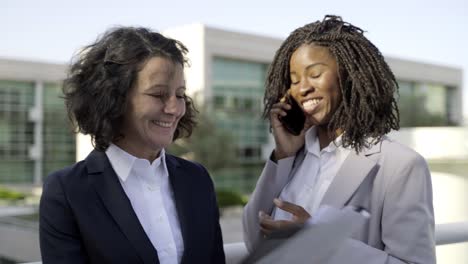 Smiling-businesswomen-with-papers-and-smartphone