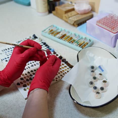 hands in pink gloves holds plastic eye. ocular prosthesis, diagnosis treatment of ophthalmic diseases, surgical operations on eyes
