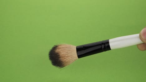 hand of man holding makeup brush against. up and down brush movement.