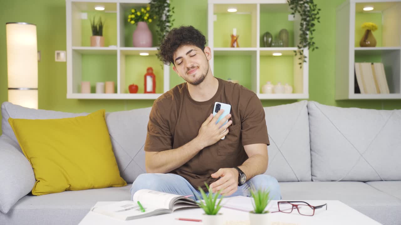 연인과 문자 메시지를 보내고 있는 십대 소년은 휴대폰을 심장에  ⁇ 고 있습니다.