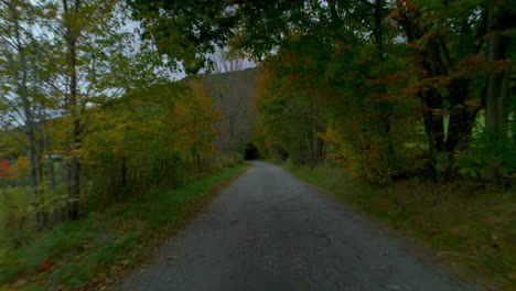 Drone-flying-low-over-a-country-gravel-road-in-the-mountains-during-fall