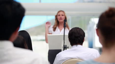 mujer rubia dando una conferencia