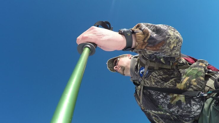 An action camera shot of a winter hiker snowshoeing up the snow covered mountains with a trekking pole on Kodiak Island Alaska