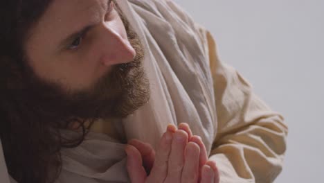 man wearing robes with long hair and beard representing figure of jesus christ looking up and praying 2