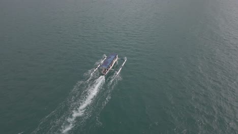 rising aerial tilts over motoring tourism boat to reveal lombok island