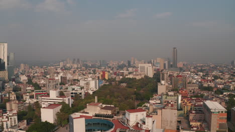 Slowly-forwards-revealing-town-park-surrounded-by-urban-housing.-Skyline-with-skyscrapers-in-background.-Mexico-City,-Mexico.