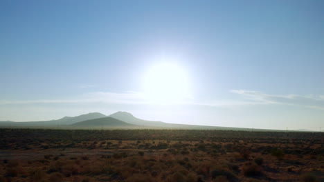 flying over the mojave desert while looking toward the distant mountains and hot sun on a summer morning