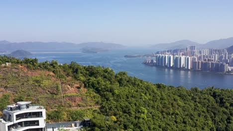 Huge-high-apartments-in-skyscrapers-with-high-mountains-of-nature-Ma-On-Shan-seen-from-the-green-trees-of-Kau-To-Shan-in-Hong-Kong