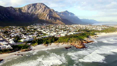 high drone pan reveals voëlklip nestled between mountain and ocean and beaches