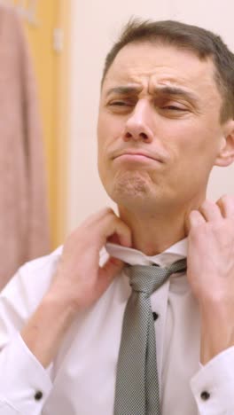 businessman getting ready in bathroom mirror, adjusting his tie