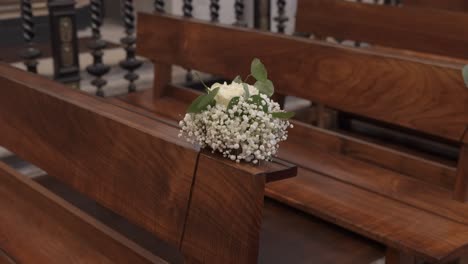 white floral arrangement with baby's breath on a wooden church pew