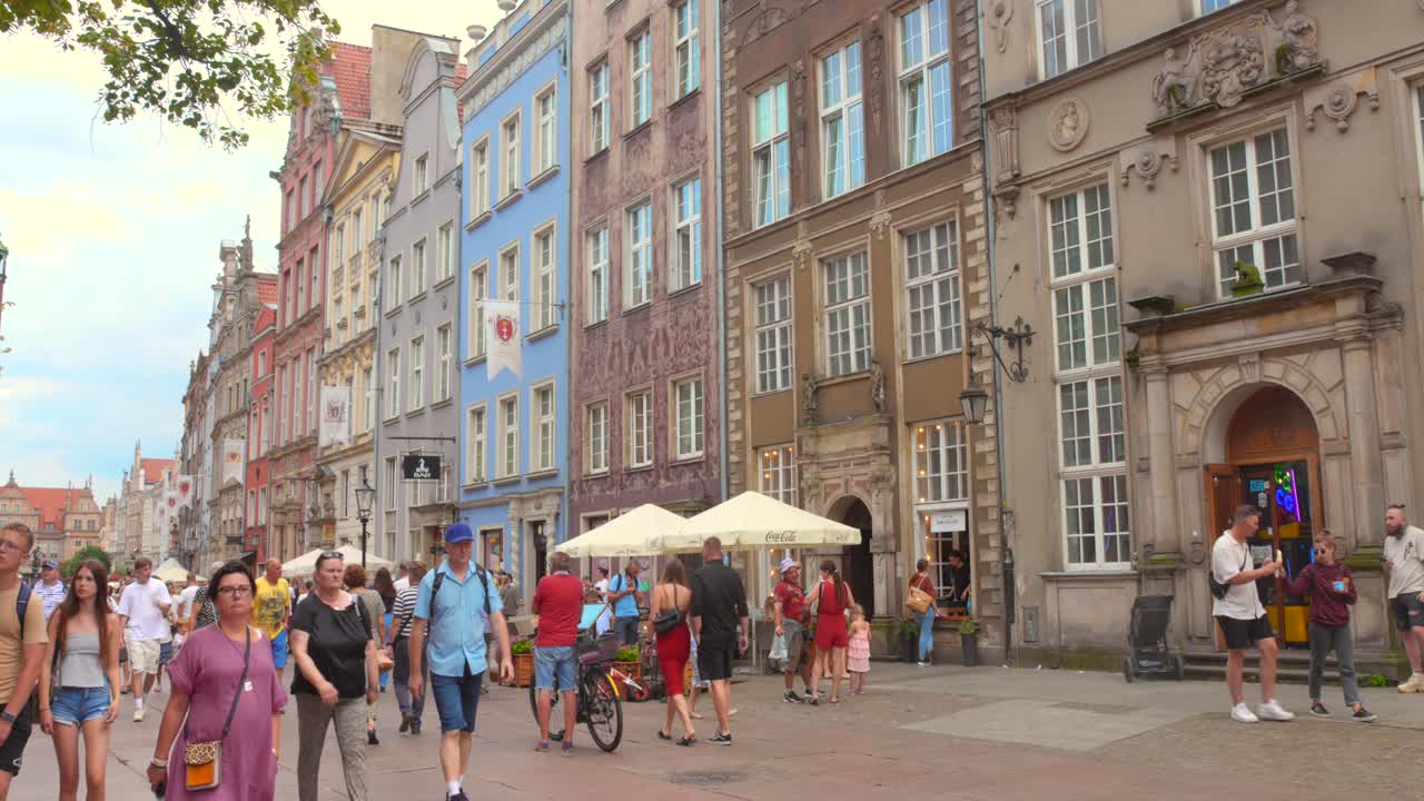 Visitors exploring historic old town with colorful polish architecture buildings in Gdansk, Poland during daytime. 4k.