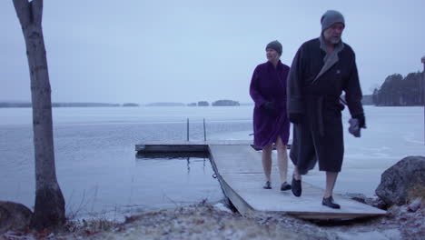 an ice bathing couple walk back to land after bathing, sweden