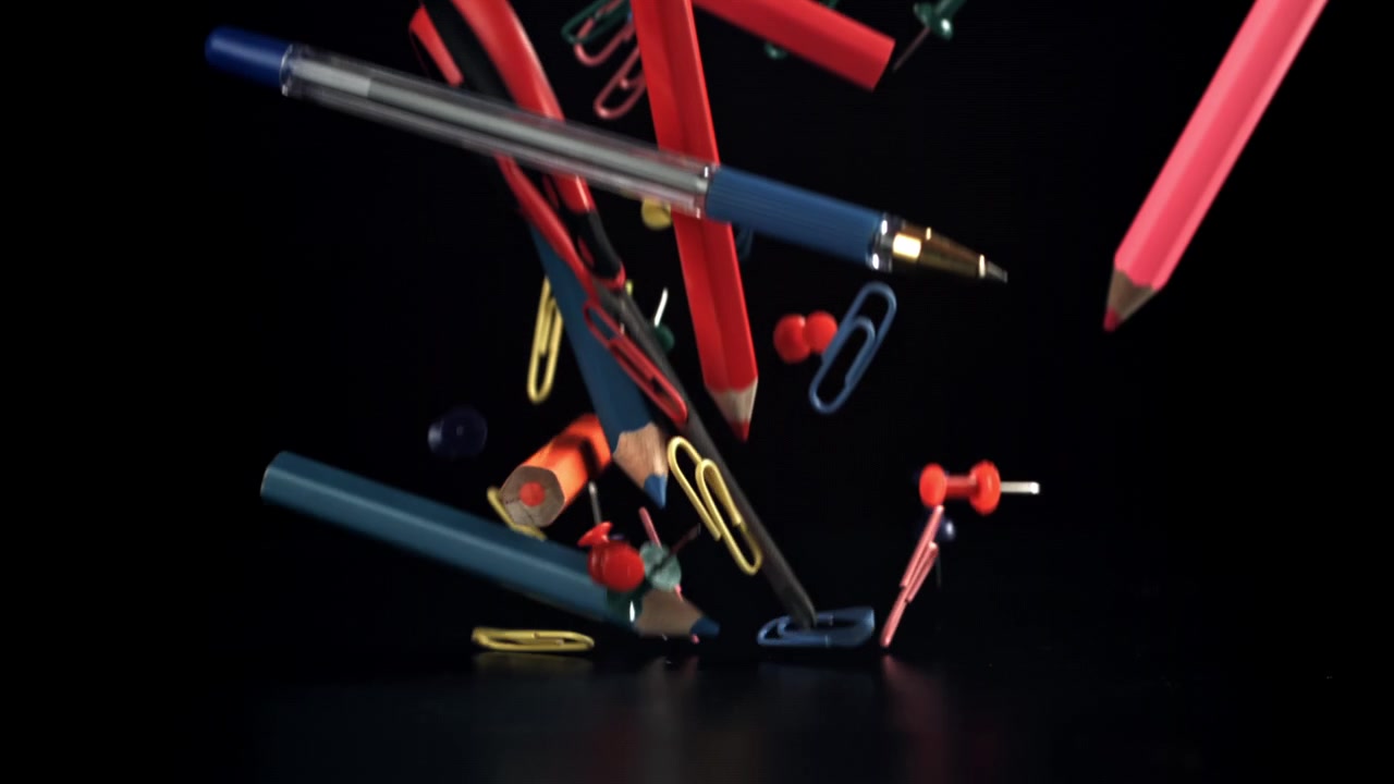 Colorful Stationery Items Falling in Slow Motion on Black Background