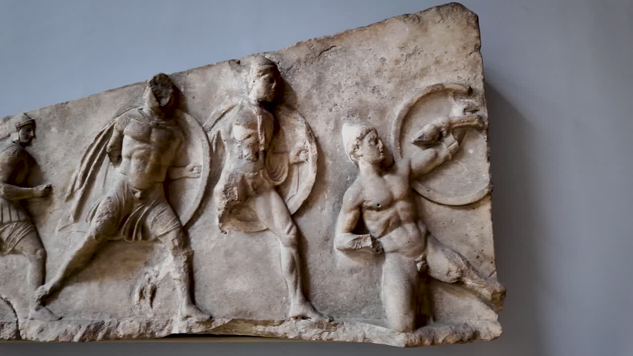 Close-up view of the high-relief battle frieze from the Nereid Monument, showcasing ancient Greek warriors in combat, exhibited at the British Museum in London