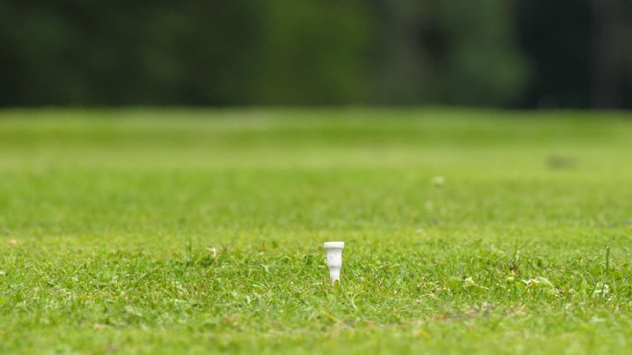 Golf driving club hits a golf ball on a tee, close up, slow motion, bokeh