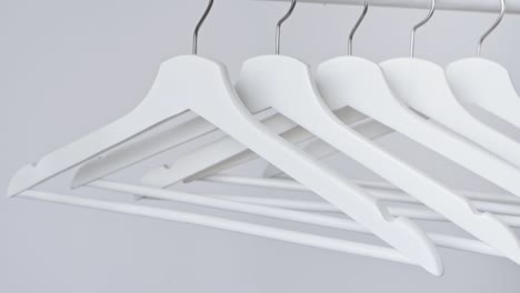 white empty wooden clothes hangers on white wall background. concept of sale in the store, discounts, minimalistic advertising. fashion, stylish metal hook hangers. equipment for home, shop, boutique