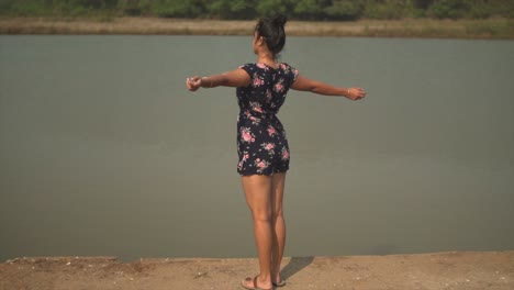 girl swinging and turning around with her arms wide open, a calm lake in the background