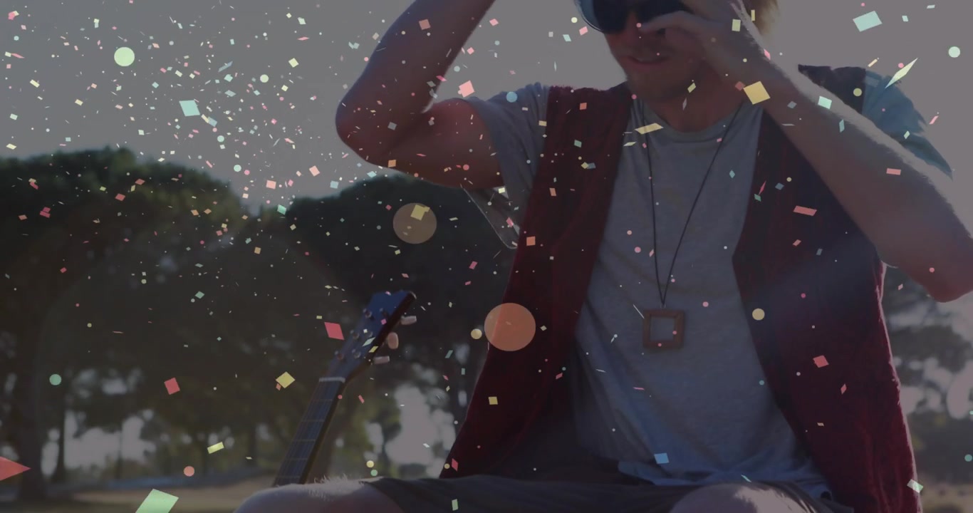 Young Man Putting on Hat Outdoors with Falling Confetti