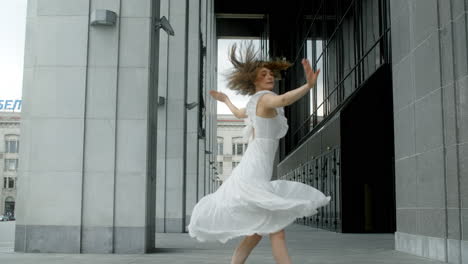 woman dancing in a white dress in a city