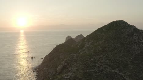 el sol se levanta tonos de rosa y amarillo sobre un mar y el horizonte