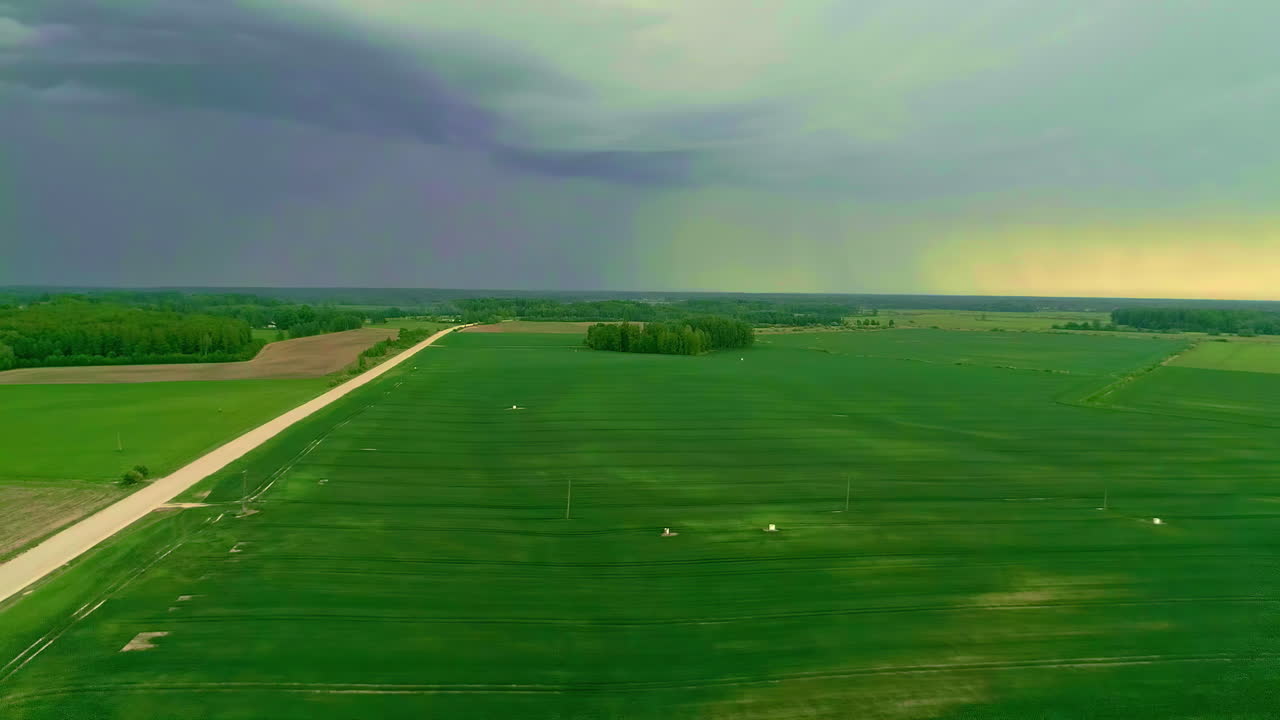 Aerial drone shot from right to left of rural pathway passing through green field