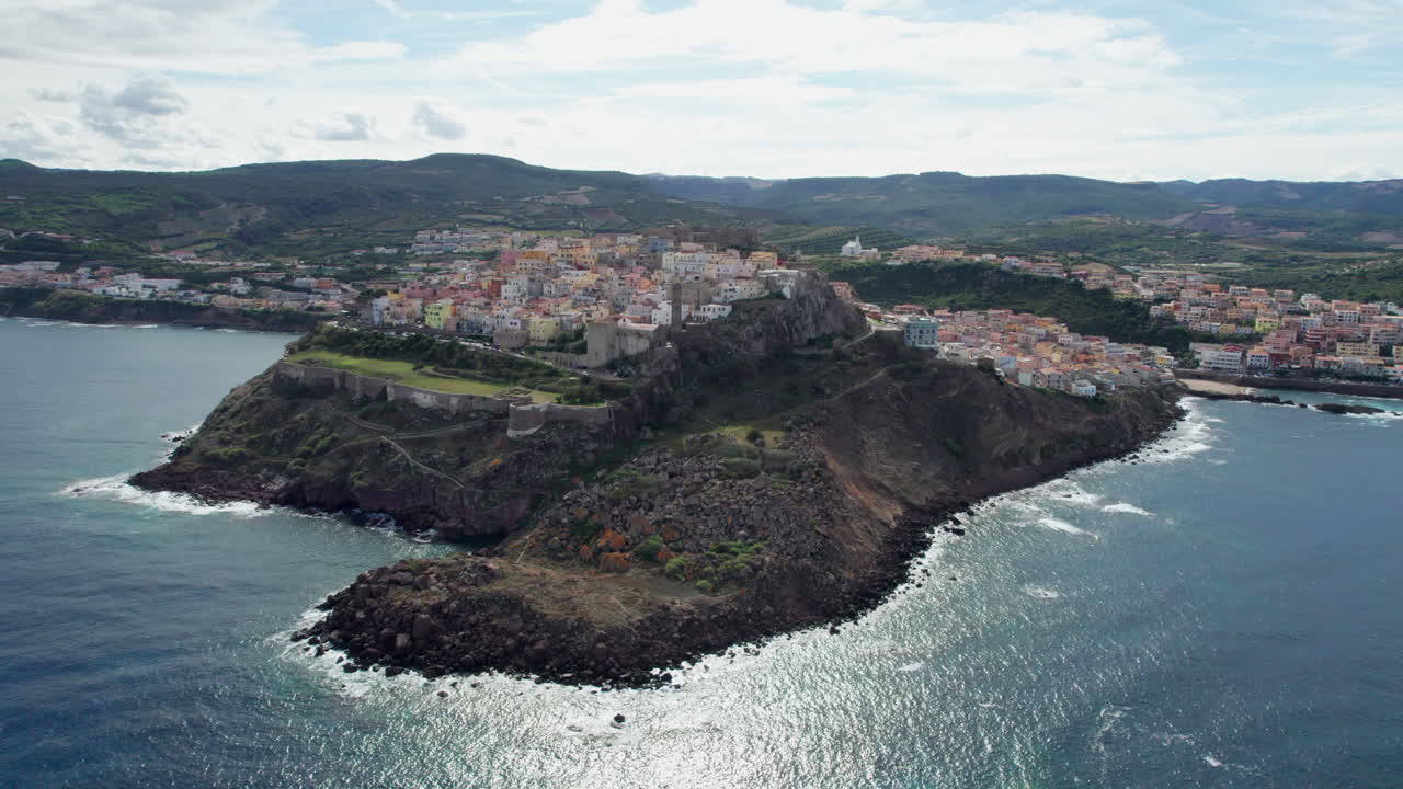 Città di Castelsardo, Sardegna: vista aerea dal mare e in circolo sulla colorata città e sulla sua torre storica sull'isola della Sardegna