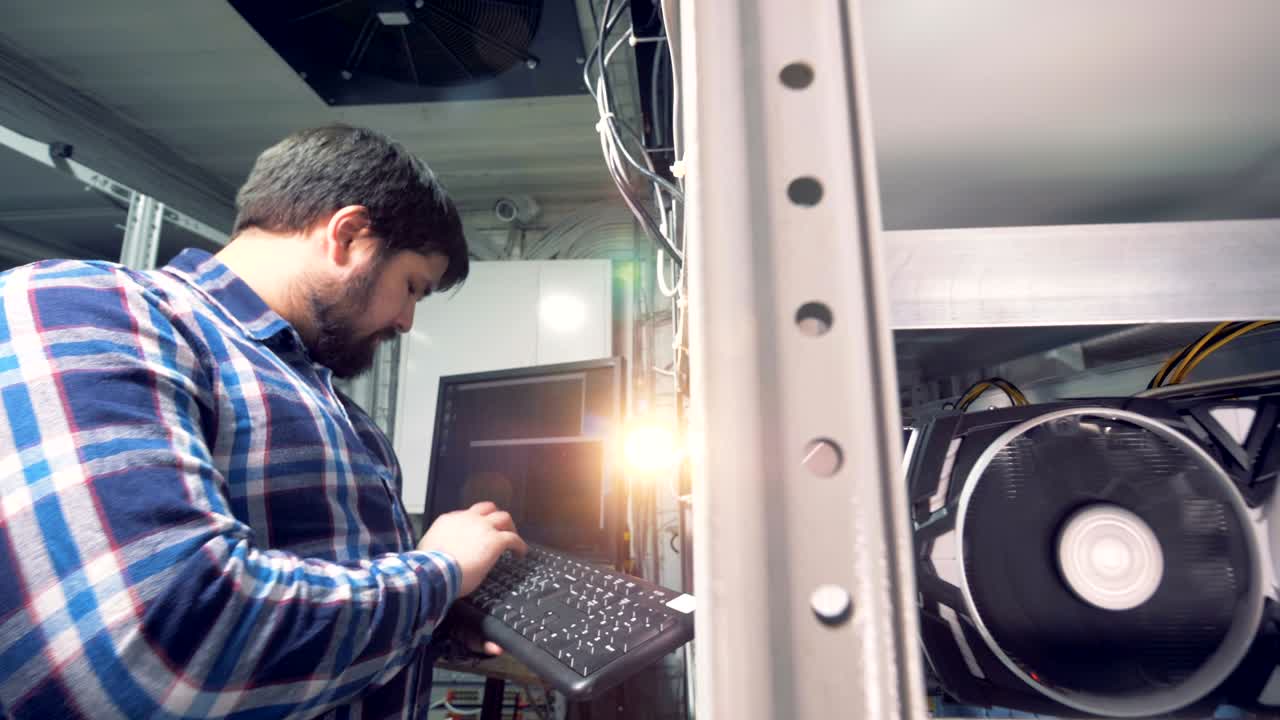 el minero masculino está escribiendo en el teclado y administrando el proceso de minería de bitcoin