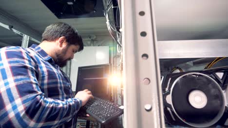 el minero masculino está escribiendo en el teclado y administrando el proceso de minería de bitcoin