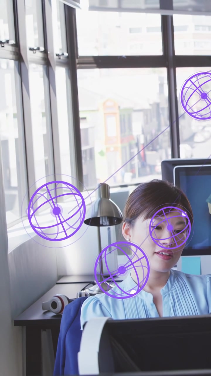 Vertical video: Staff sitting at desk AR orbs popping drifting over face causing turns to view data