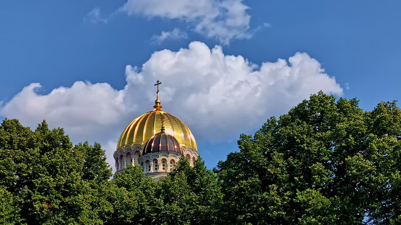 Picturesque view of a golden plated tomb with Cross on top with white clouds in sky