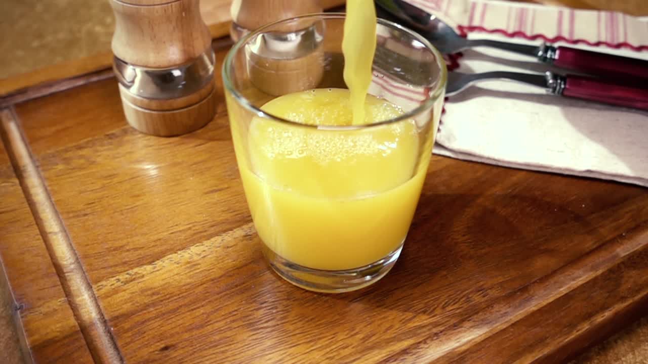 jugo de naranja en un vaso, el desayuno de la mañana, cámara lenta con seguimiento de rotación.