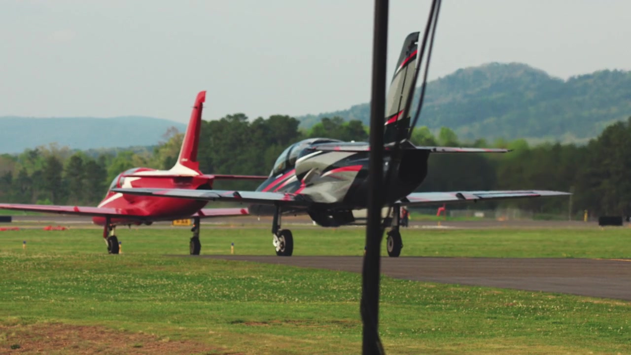 Due piccoli aerei a reazione rullano lentamente lungo una pista di un aeroporto durante il giorno