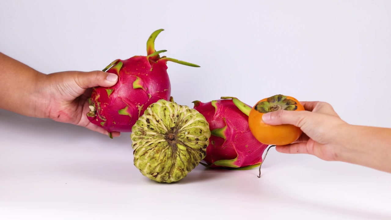 Mani che dispongono frutto del drago, cherimoya e cachi