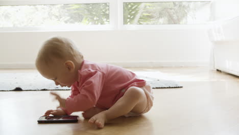 adorable baby girl sitting on floor and playing with smartphone
