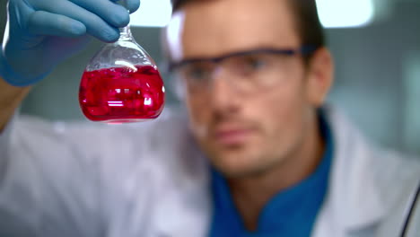 frasco de vidrio con líquido en las manos del científico. investigación médica en el laboratorio