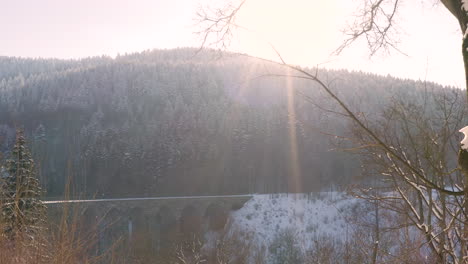 winter sun shining on a snowy mountain valley with a stone viaduct