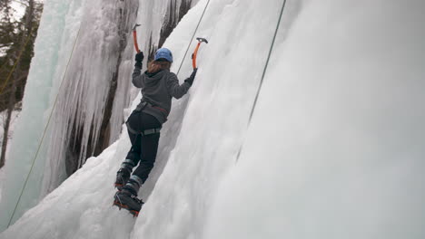 reveal shot of a mountaineer ice climbing a frozen rock face