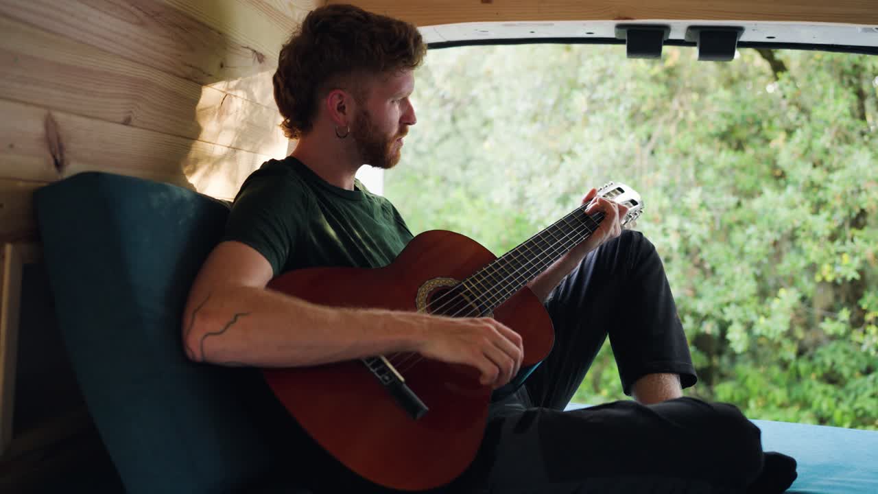 Man playing guitar in a van