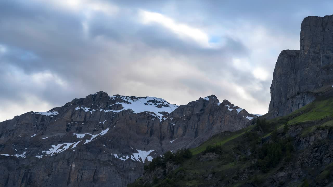 Mountain ranges in a beautiful summer landscape. Time-lapse of the clouds. The sky is cloudy at sunset. Taken in the Swiss Alps from a valley called Leukerbad